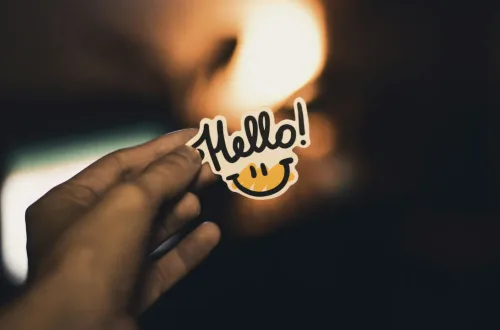 A photo of a man's hand holding a small "hello" sign.