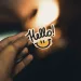 A photo of a man's hand holding a small "hello" sign.